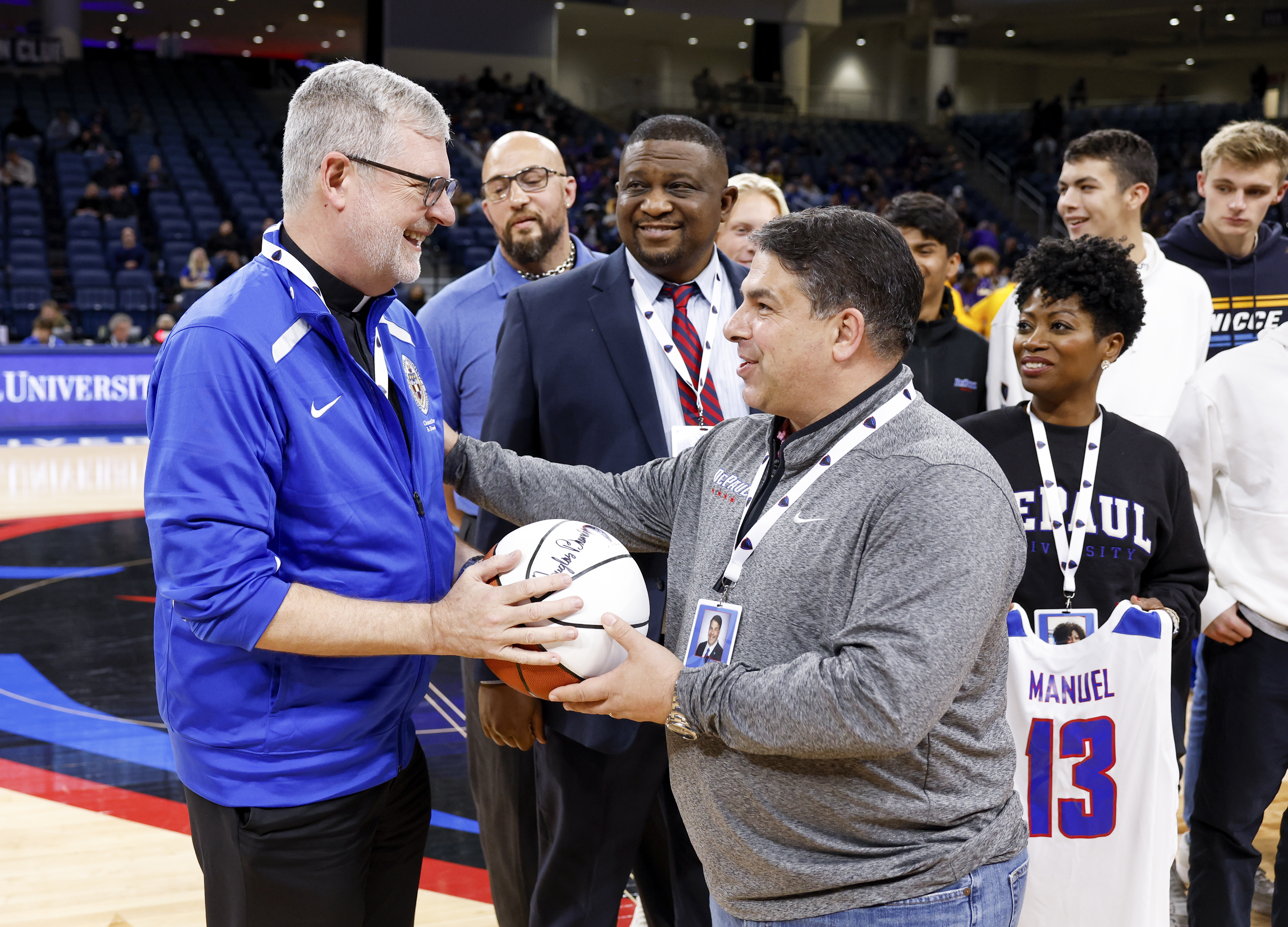 President Rob Manuel was recognized during the Nov. 11 basketball men’s game vs. Western Illinois. In this photo, Manuel is joined by DePaul Chancellor and former President Rev. Dennis H. Holtschneider, C.M., Vice President and Director of Athletics DeWayne Peevy, and Manuel’s wife Wilmara, holding a jersey for the university’s 13th president. The Blue Demons won 86-74. (DePaul University/Steve Woltmann)